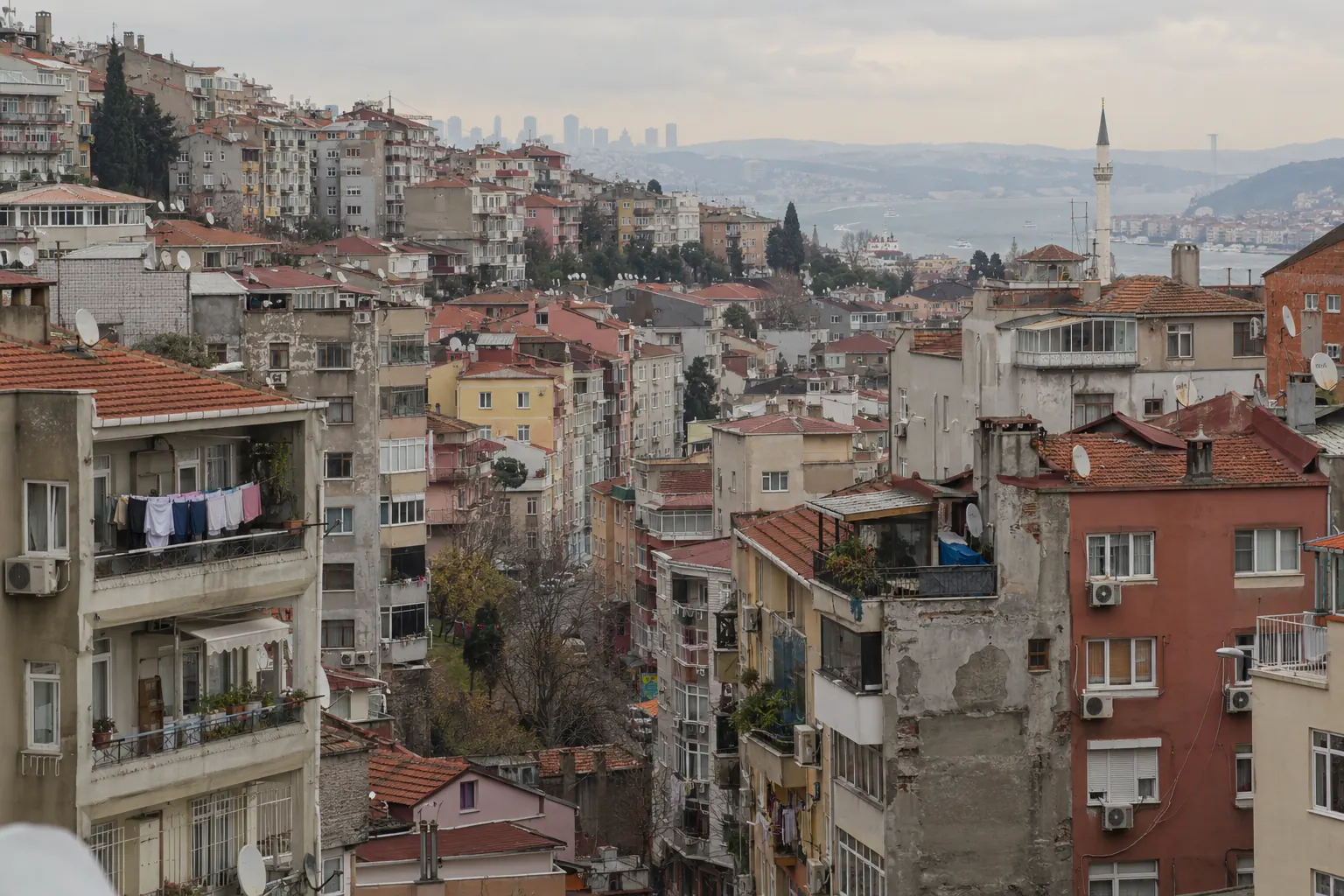 Dense hillside apartment blocks in Istanbul with the Bosphorus in the distance